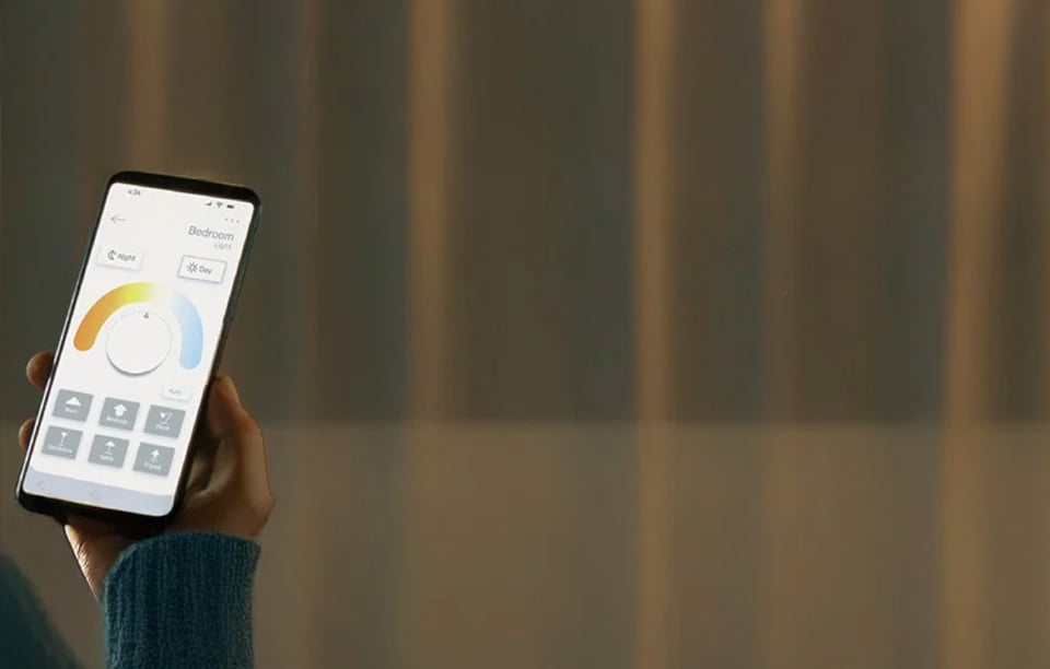 Opplyst trestamme med lyslenke, tre lykter med LED-lys og tepper på en terrasse i kveldsbelysning.