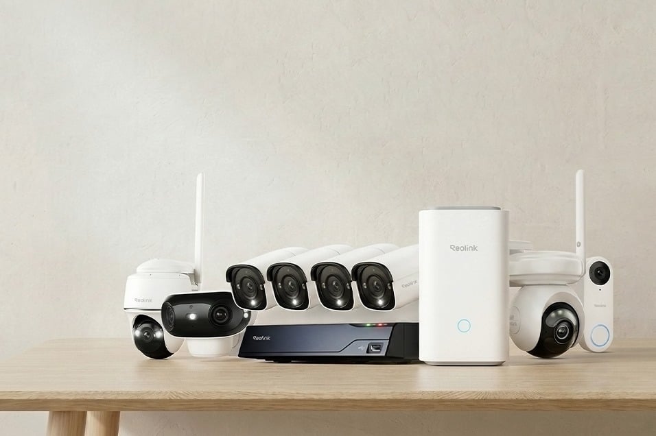 Reolink övervakningssystem med flera kameror, NVR-inspelare och hubb placerade på ett bord mot ljus bakgrund.