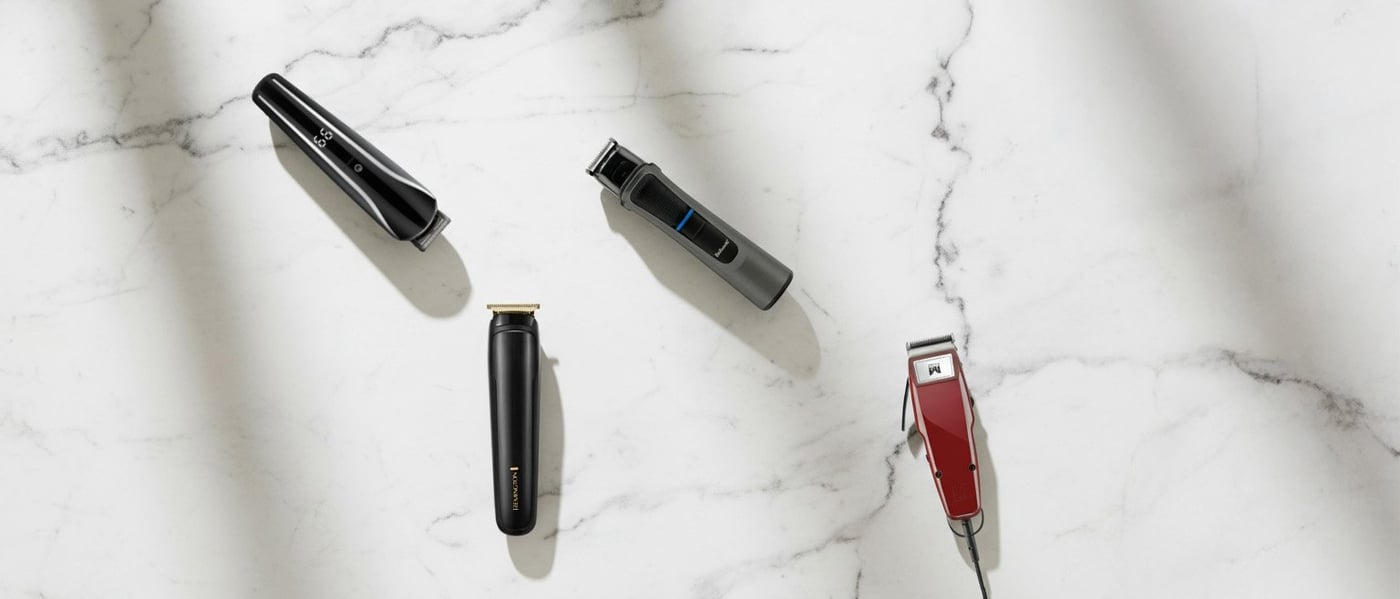 Svart och guldfärgad Remington-trimmer med tillbehör och kam, placerade mot ett mönstrat svartvitt underlag.