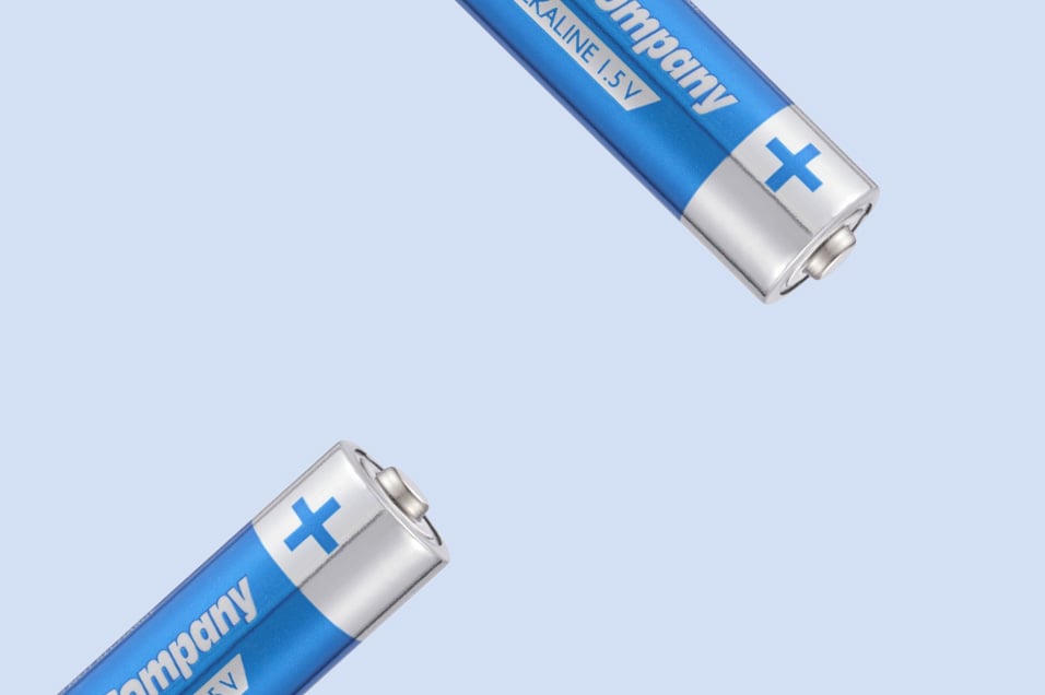 Två blå AA-alkaliska batterier med tydlig plussymbol mot ljusblå bakgrund.