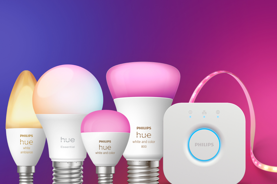 Flera Philips Hue smarta glödlampor i olika storlekar, en Bridge och en LED-ljusslinga mot lila och rosa bakgrund.