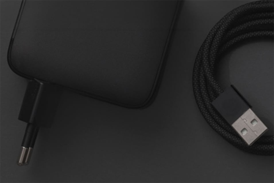 Linocell lader og flettet USB-kabel mot mørk bakgrunn.
