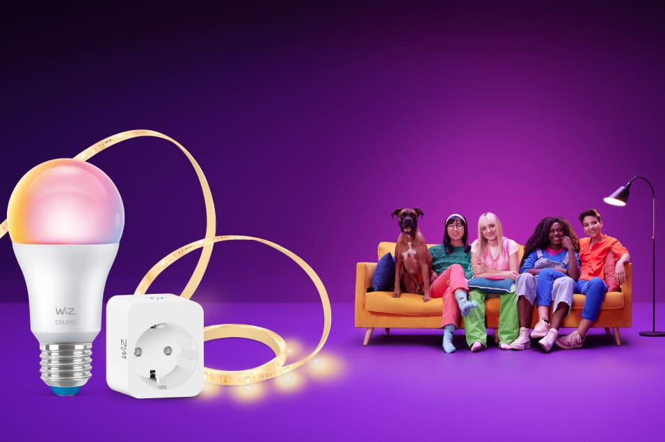 WiZ smart glödlampa, LED-list och smart plug mot lila bakgrund med ungdomar och hund på gul soffa i färgstark miljö.