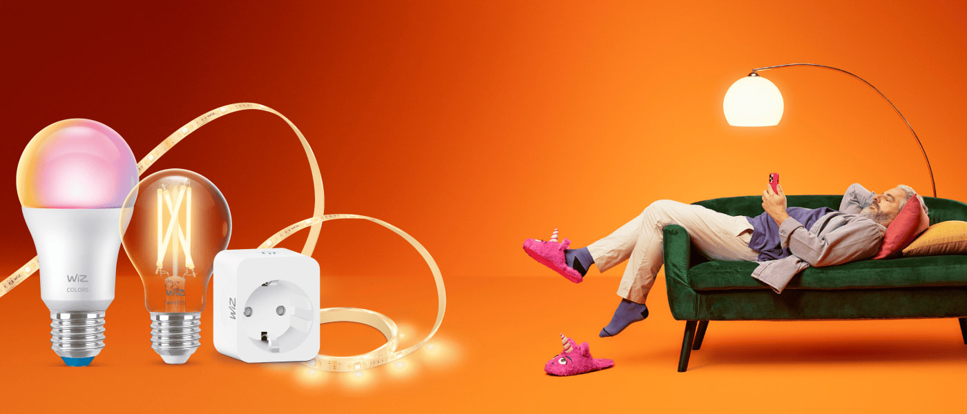 WiZ smarta lampor, LED-list och kontaktplugg till vänster; till höger ligger en man på grön soffa i orange upplyst rum.