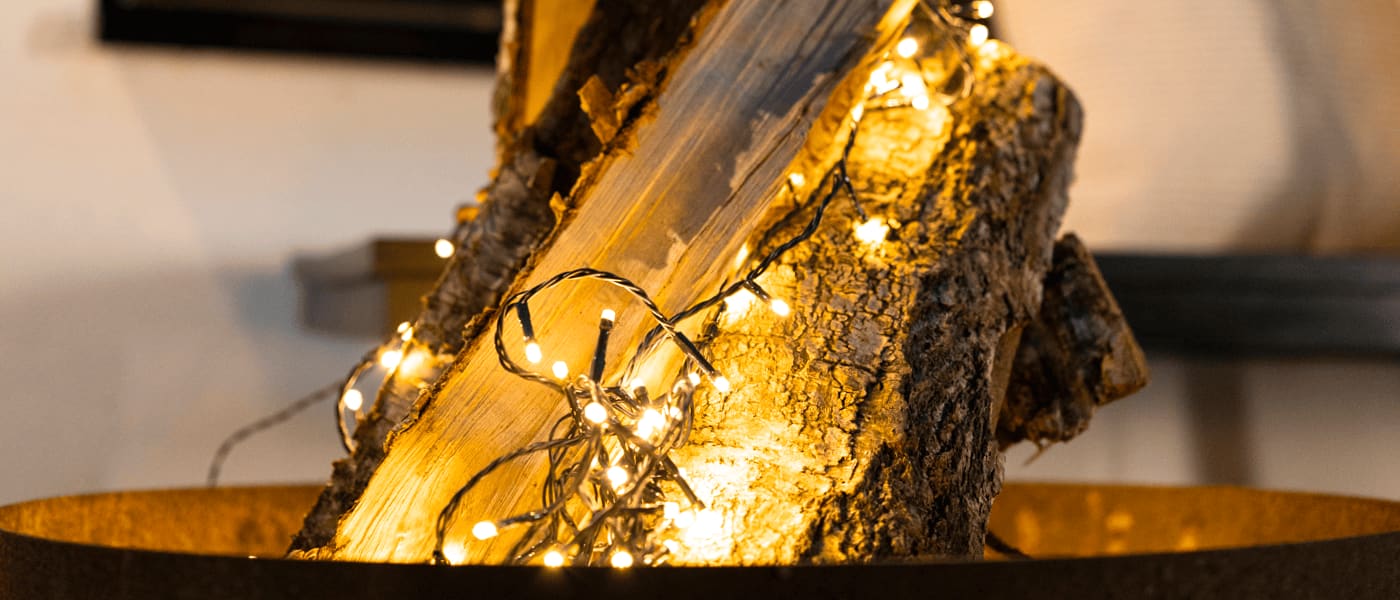 Gul varmvitt ljusslinga lindad runt en vedklabbe i en rustik miljö, skapar stämningsfull julbelysning.