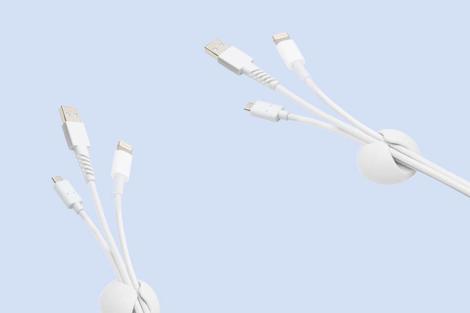 Två vita kabelhållare med vita USB- och laddkablar monterade i båda.