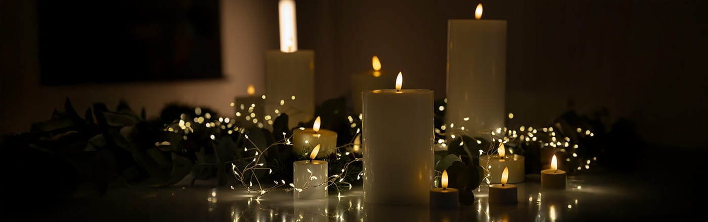 Elektriska LED-ljus i olika storlekar omgivna av gröna kvistar och ljusslingor i varm, mörk miljö.