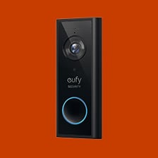 Eufy Security videodörrklocka i svart med kamera och blå LED-ring mot orange bakgrund
