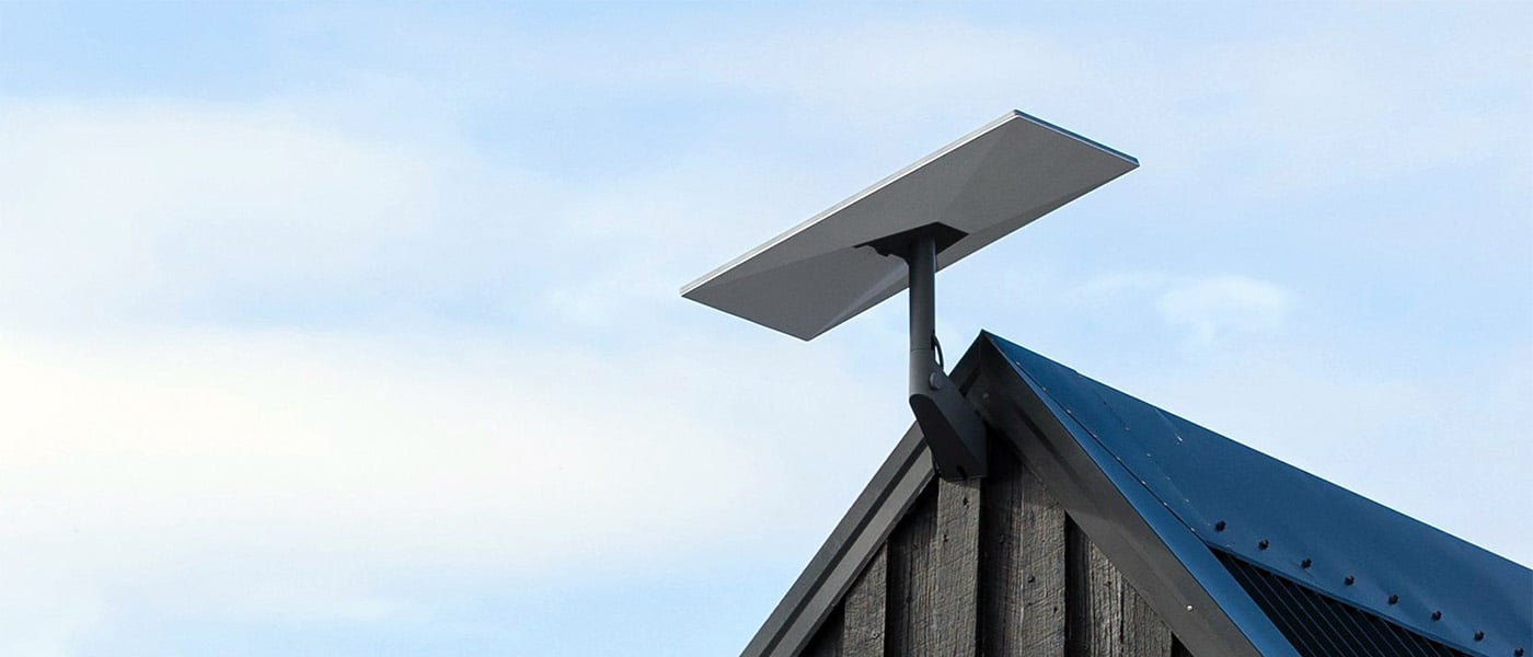 Starlink-antenn monterad på taknock mot molnig himmel.