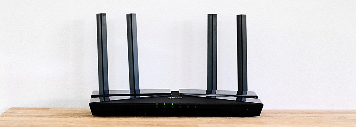 Svart trådlös router från TP-Link med fyra upprättstående antenner och tre gröna indikatorlampor på framsidan.