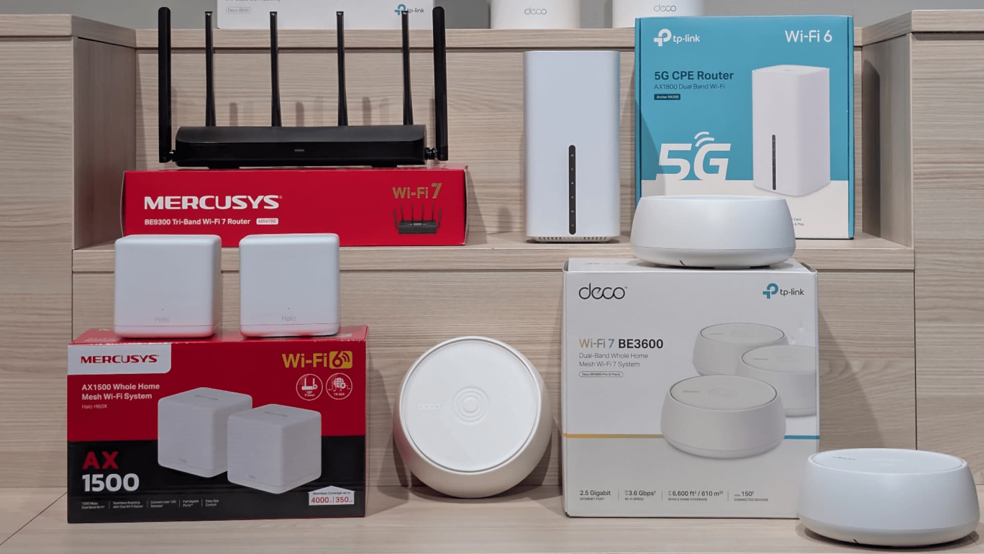 Flere mesh-rutere og Wi-Fi-systemer fra TP-Link og Mercusys, inkludert modeller med Wi-Fi 6 og Wi-Fi 7, plassert på trepodier.