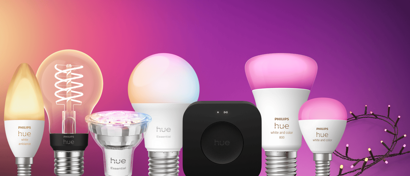 Flera smarta Philips Hue-lampor i olika former och färger mot rosa-lila bakgrund, samt en svart Hue Bridge i mitten.