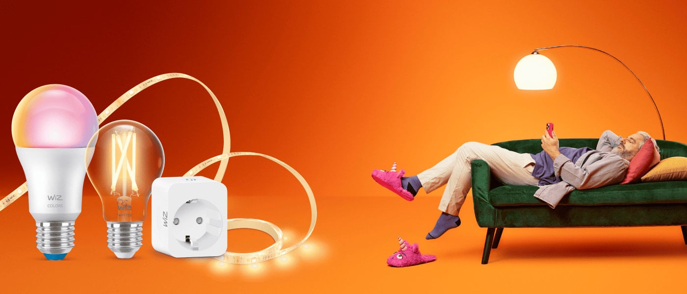 WiZ smarta lampor, LED-list och kontaktplugg till vänster; till höger ligger en man på grön soffa i orange upplyst rum.