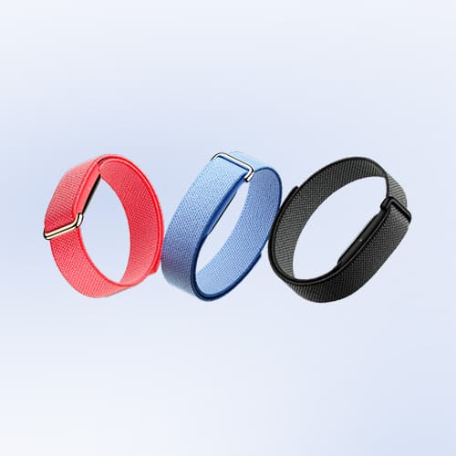 Tre fitness-armband i olika färger – rött, blått och svart – mot en ljusgrå bakgrund.